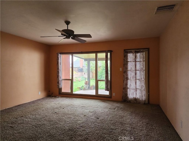 carpeted empty room featuring visible vents and ceiling fan