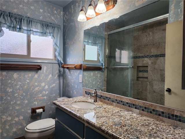 full bathroom featuring vanity, toilet, a shower stall, and wallpapered walls