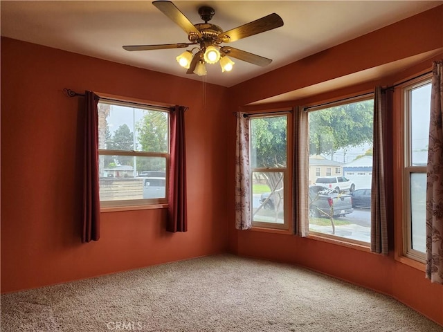 carpeted empty room with plenty of natural light and a ceiling fan