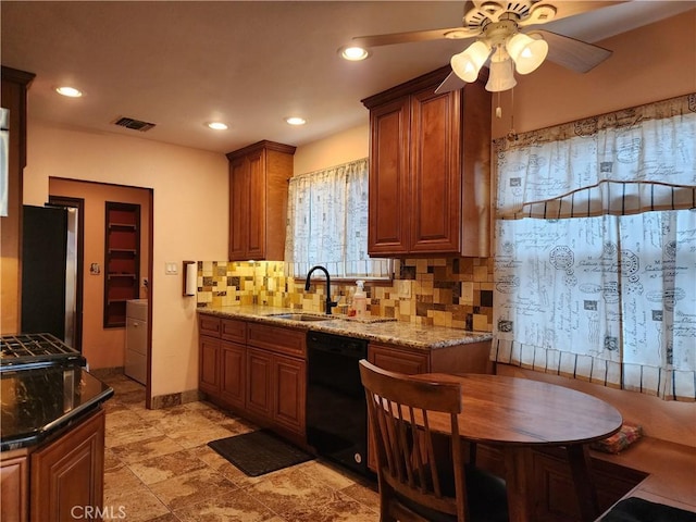 kitchen with light stone counters, freestanding refrigerator, a sink, decorative backsplash, and dishwasher