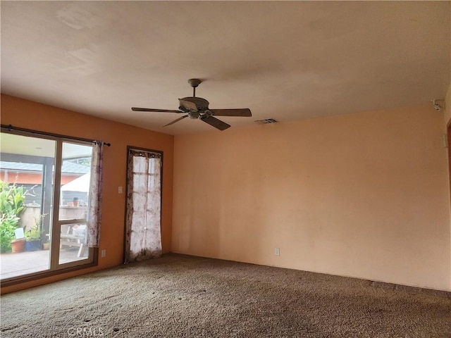 carpeted spare room with visible vents and a ceiling fan