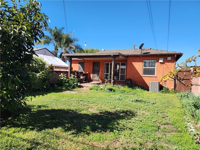 back of property featuring a yard and stucco siding