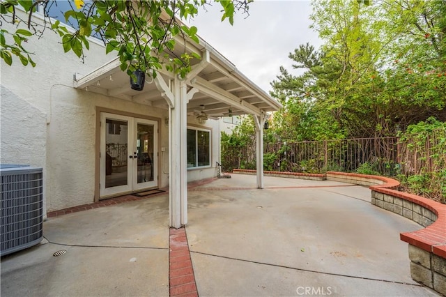 view of patio / terrace with a ceiling fan, french doors, fence, and central AC