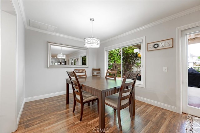 dining room featuring visible vents, crown molding, baseboards, and wood finished floors