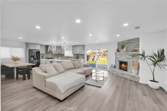 living room with a fireplace, recessed lighting, light wood-style floors, and visible vents