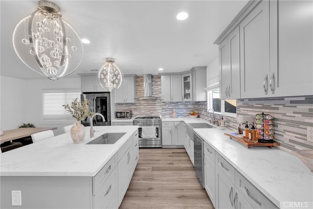 kitchen with a sink, stainless steel appliances, backsplash, and wall chimney exhaust hood