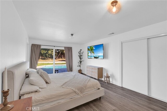 bedroom with visible vents, a closet, wood finished floors, and access to outside