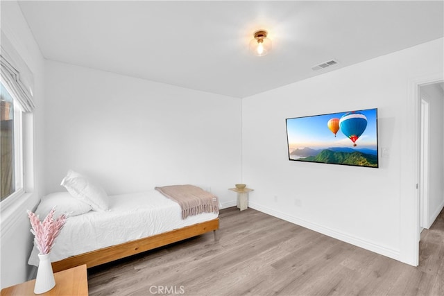 bedroom with visible vents, baseboards, and wood finished floors