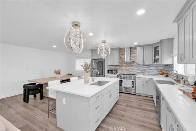 kitchen featuring a sink, stainless steel appliances, a kitchen breakfast bar, and wall chimney range hood