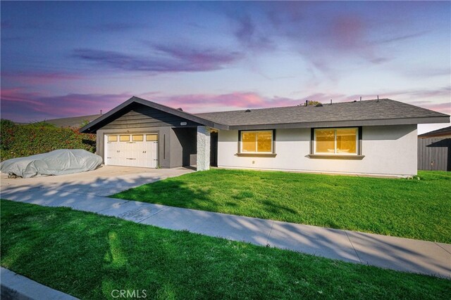 ranch-style home featuring a front yard, roof with shingles, driveway, stucco siding, and a garage