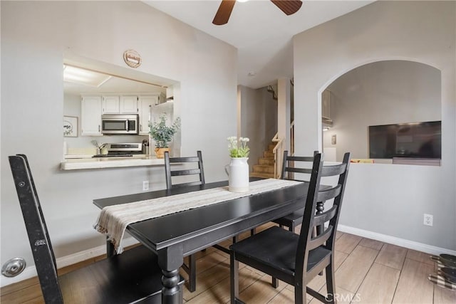 14039 Astoria St Unit 120, Sylmar, CA 91342 - dining room featuring a ceiling fan, arched walkways, stairway, and light wood-style flooring