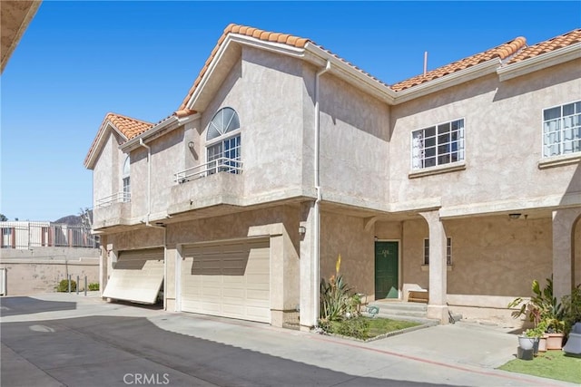 14039 Astoria St Unit 120, Sylmar, CA 91342 - view of front facade with stucco siding, a tiled roof, an attached garage, driveway, and a balcony