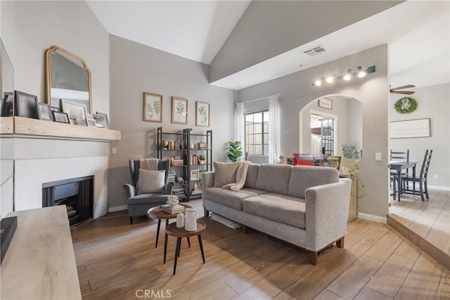 14039 Astoria St Unit 120, Sylmar, CA 91342 - living area featuring light wood-style flooring, arched walkways, lofted ceiling, a fireplace, and a ceiling fan