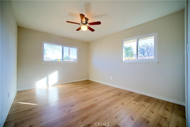 spare room with ceiling fan, baseboards, plenty of natural light, and wood finished floors