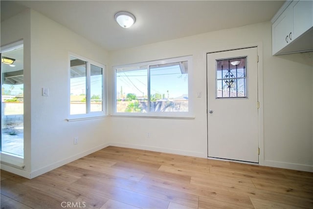 doorway featuring baseboards and light wood finished floors