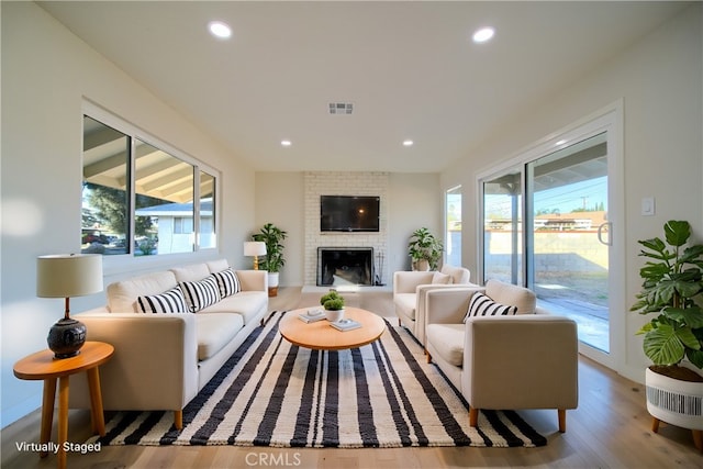 living area featuring visible vents, a healthy amount of sunlight, wood finished floors, and a fireplace