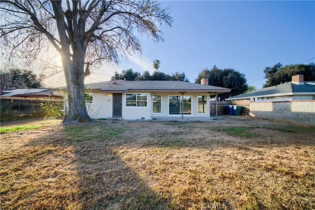 view of front of home with a front yard, a fenced backyard, and a chimney