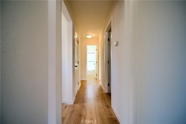 hallway featuring light wood-type flooring and baseboards