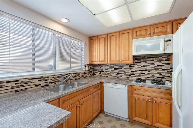 kitchen featuring backsplash, a sink, white appliances, and light countertops