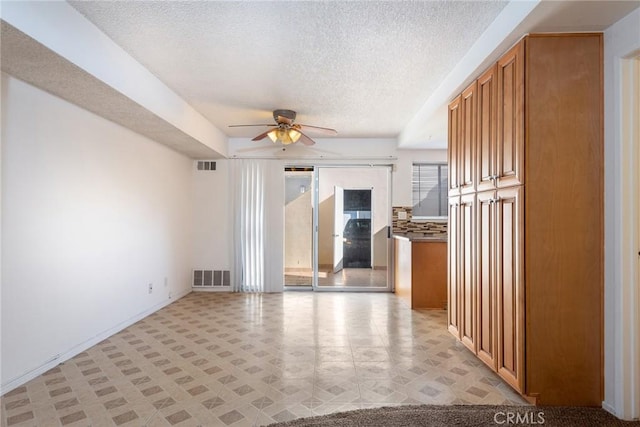 spare room with baseboards, a ceiling fan, a textured ceiling, and visible vents