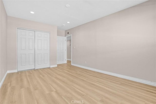 unfurnished bedroom featuring recessed lighting, a closet, baseboards, and light wood-style flooring