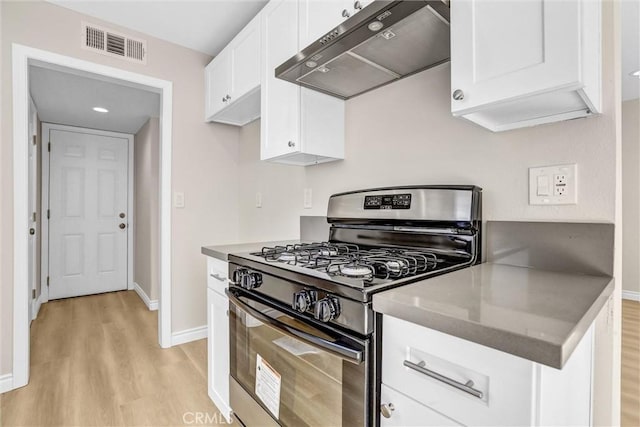 kitchen with range with gas stovetop, visible vents, light wood-style flooring, white cabinets, and under cabinet range hood