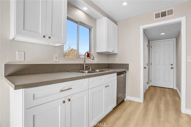 kitchen with visible vents, a sink, stainless steel dishwasher, light wood-style floors, and white cabinets