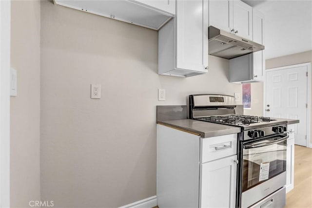 kitchen featuring under cabinet range hood, gas range, light wood-style flooring, and white cabinetry