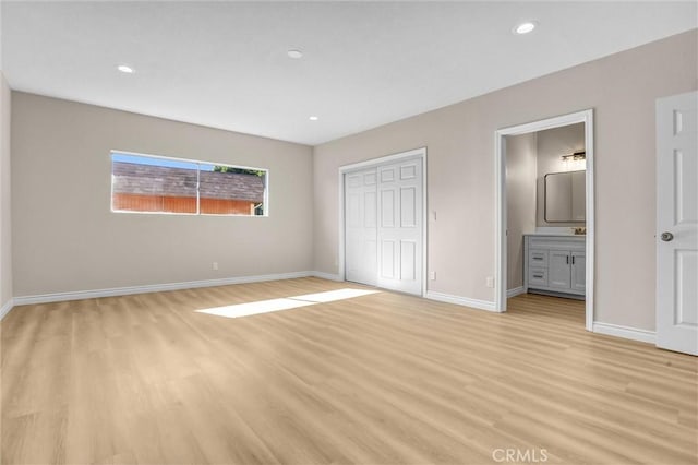 unfurnished bedroom featuring baseboards, recessed lighting, light wood-style floors, a closet, and ensuite bath