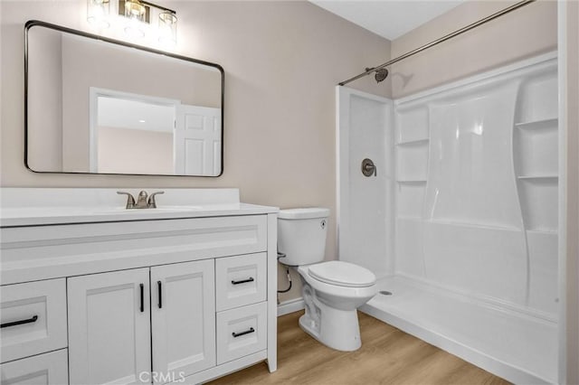 bathroom featuring toilet, vanity, walk in shower, and wood finished floors