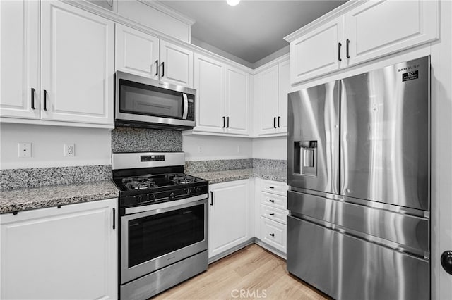 kitchen featuring white cabinetry, light stone counters, light wood-style floors, and stainless steel appliances