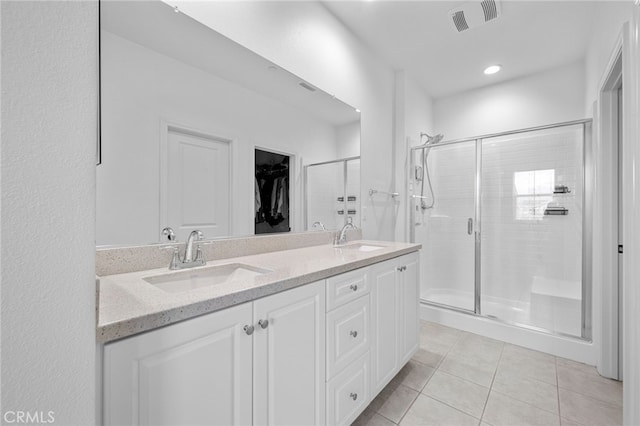 full bath with visible vents, a stall shower, and a sink