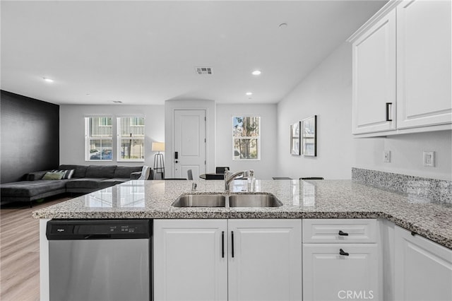 kitchen with visible vents, dishwasher, a peninsula, white cabinets, and a sink