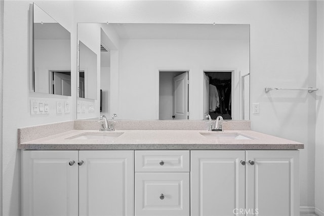 bathroom featuring a sink, a walk in closet, and double vanity