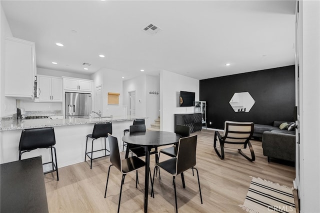 dining area featuring recessed lighting, light wood-type flooring, visible vents, and an accent wall