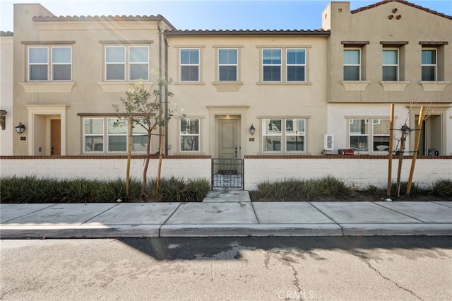 view of front of property with stucco siding, brick siding, and a fenced front yard