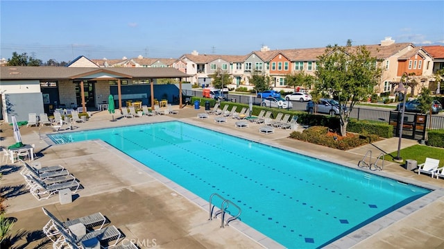 community pool with a residential view, a patio, and fence