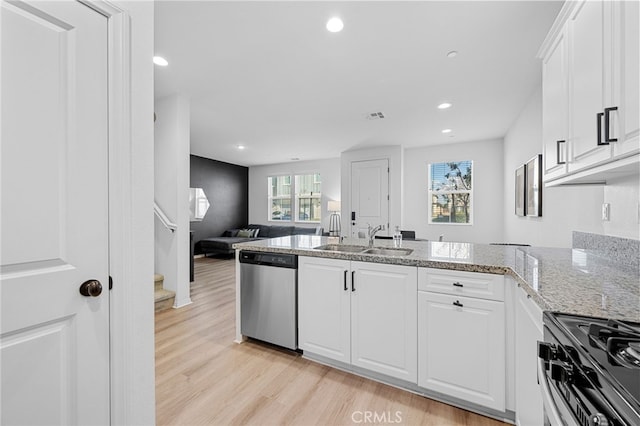 kitchen with light wood-style flooring, appliances with stainless steel finishes, a peninsula, white cabinetry, and a sink