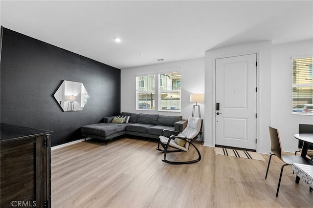 living room with light wood finished floors, visible vents, and baseboards