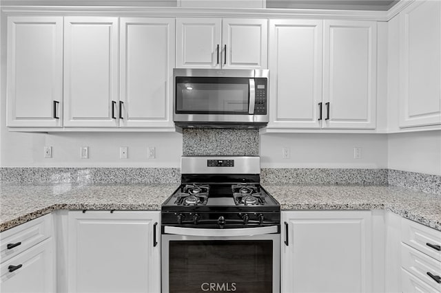 kitchen with white cabinetry, light stone counters, and stainless steel appliances