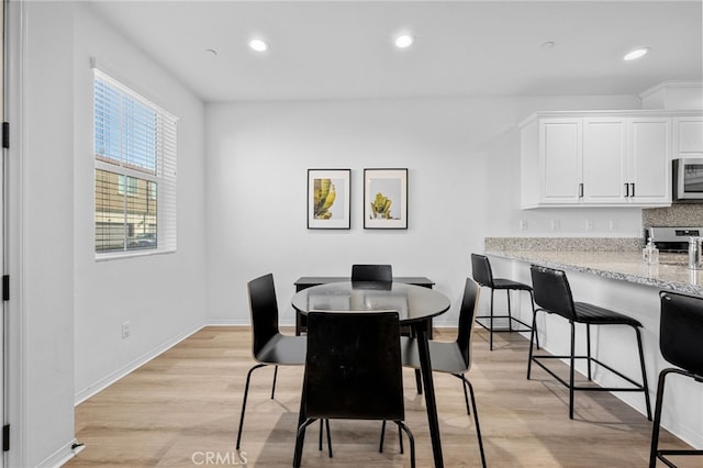 dining room with recessed lighting, baseboards, and light wood finished floors