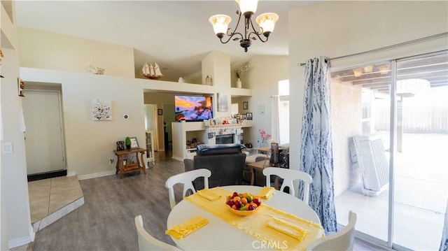 dining area featuring a stone fireplace, plenty of natural light, wood finished floors, and a chandelier