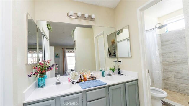 full bath featuring a wealth of natural light, tiled shower, and a sink