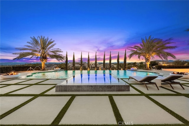 pool at dusk featuring a patio, a community pool, and a water play area