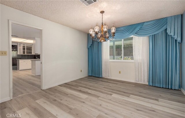 23187 Glendora Dr, Grand Terrace, CA 92313 - unfurnished room featuring a chandelier, a textured ceiling, light wood-style floors, and baseboards