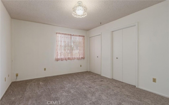 23187 Glendora Dr, Grand Terrace, CA 92313 - unfurnished bedroom with multiple closets, carpet floors, and a textured ceiling