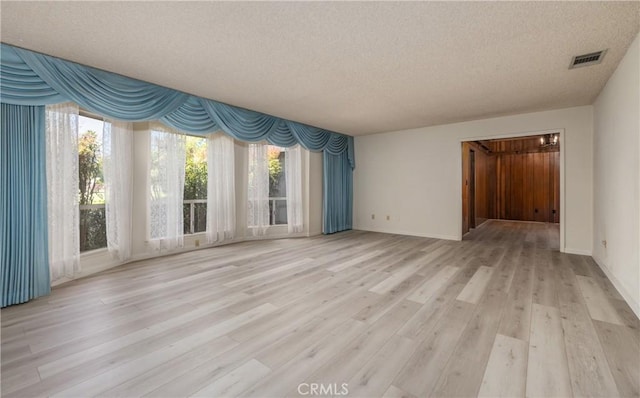 23187 Glendora Dr, Grand Terrace, CA 92313 - unfurnished living room featuring a textured ceiling, light wood-style floors, and baseboards