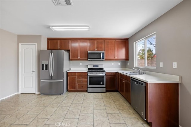 kitchen with baseboards, visible vents, a sink, light countertops, and appliances with stainless steel finishes