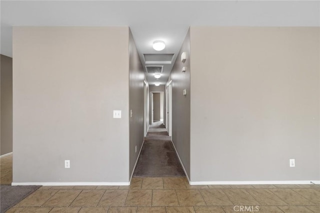 hallway with visible vents, baseboards, and attic access