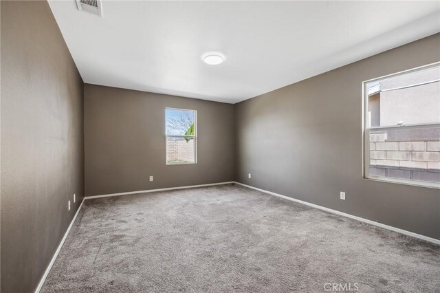 spare room with visible vents, baseboards, and carpet